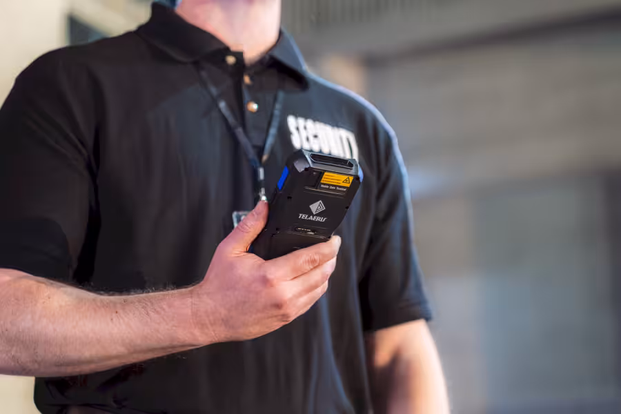 close up of a security guard holding an XPressEntry No-Comm handheld badge reader with no camera