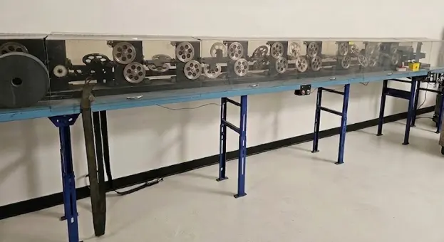 Long workbench machine with rows of gears and spools used to manufacture Wiegand wire cards